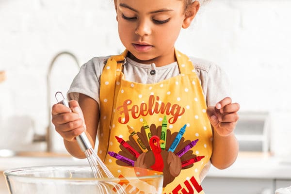 Portfolio: Girl with mixing bowl wearing Crayola-branded apron that says "Feeling Thankful" for seasonal design collections.